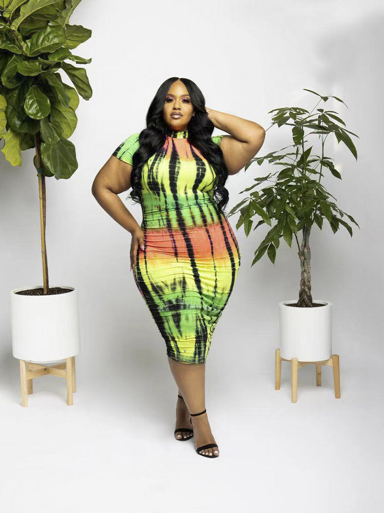 Plus-size woman posing in a tie-dye bodycon dress with short sleeves and a mock neckline.