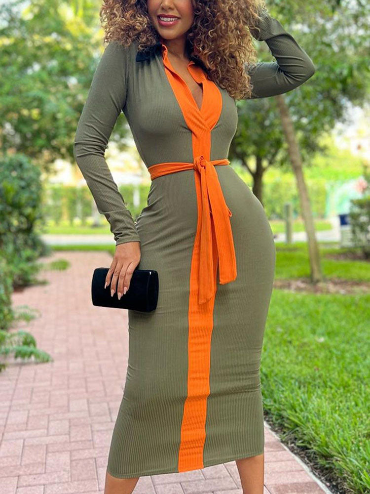 Woman wearing a long-sleeved, bodycon midi dress with olive green and orange color-blocking and a matching belt, standing outdoors.