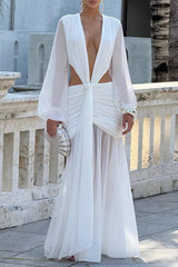 White floor-length dress with a deep V-neck, cut-out details, and a sheer skirt, modeled outdoors.