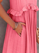 close-up of a woman's hand in the pocket of a pink tiered ruffle maxi dress