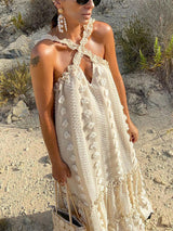Side view of the woman wearing the cream-colored maxi dress, showcasing the halter neckline and floral details.