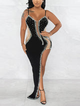 Woman posing in a black high-slit gown with crystal embellishments and sheer side panels.