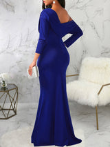 Rear view of a woman wearing a long royal blue asymmetrical dress with long sleeves and a mermaid hemline.