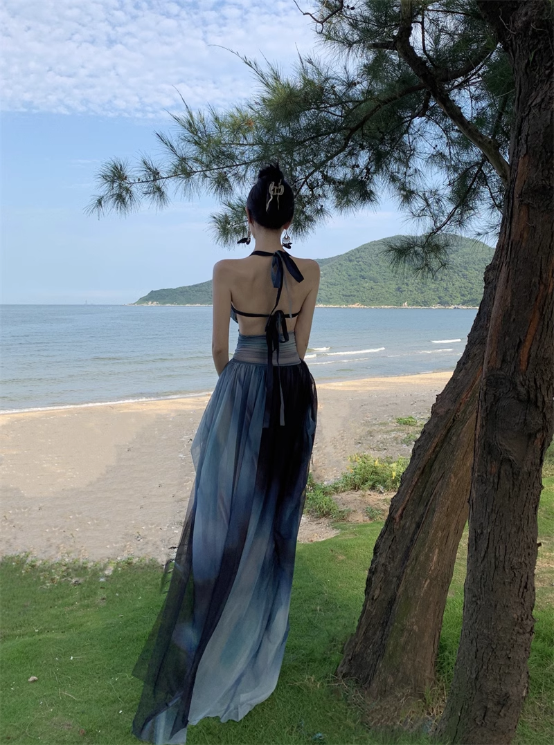 Back view of a woman in an ombre halter dress, showcasing the open back and flowing skirt.