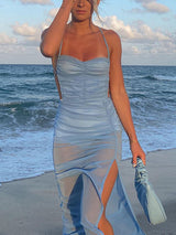 Close-up of a woman in a light blue ruched mesh maxi dress with a high slit.