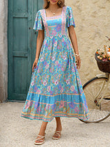 Front view of a woman in a blue floral print maxi dress, showcasing the square neckline and tiered skirt.