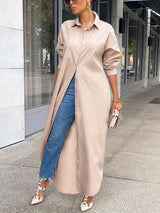 Woman wearing a long beige button-down shirt dress with blue jeans and beige high heels