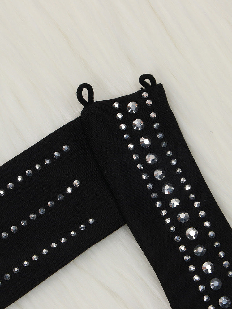 Close-up of black fabric adorned with rows of clear rhinestones of varying sizes.