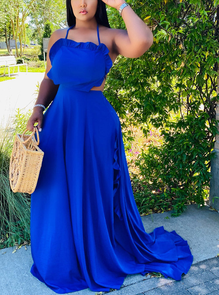 Woman wearing a royal blue two-piece maxi dress with a halter neckline and ruffled trim, holding a straw bag.