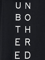 Close-up of 'Unbothered' graphic text on a black hooded dress.