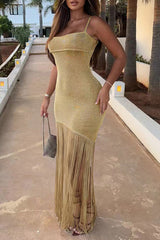 Woman in a gold sparkly maxi dress with fringe and a high slit, outdoors