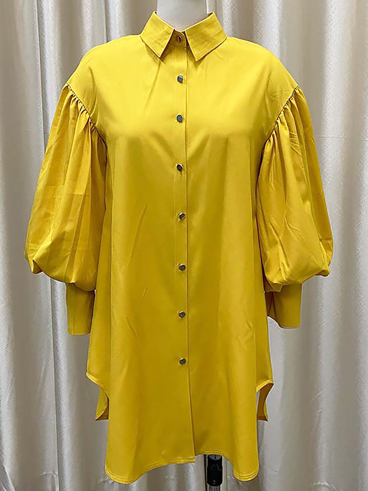 A mustard yellow oversized shirt dress with balloon sleeves and a high-low hem displayed on a mannequin.