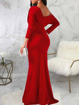 back view of a woman in a red one-shoulder draped long sleeve mermaid formal gown