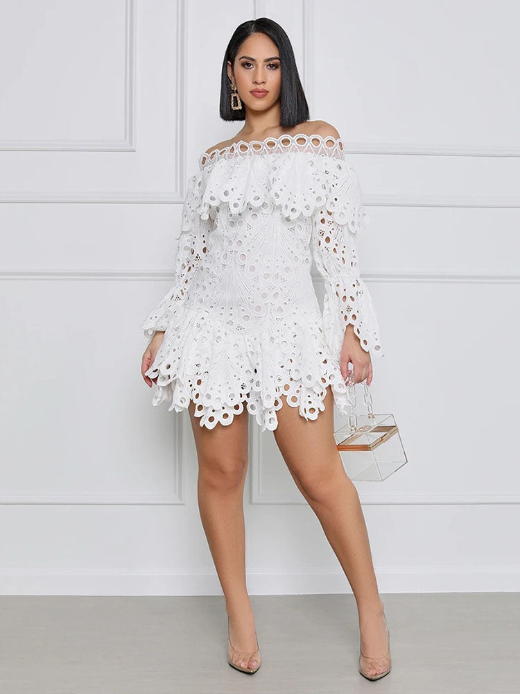 Model wearing a white off-the-shoulder eyelet lace mini dress with bell sleeves and tiered skirt, holding a clear clutch.