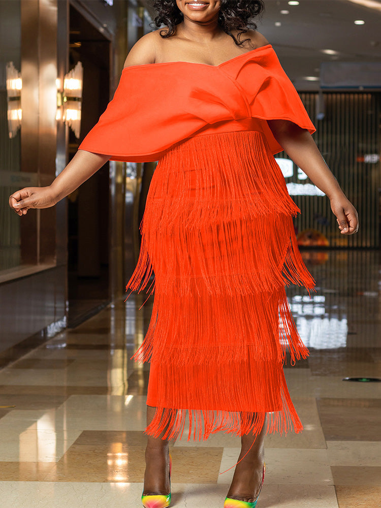 Woman wearing a bright orange off-the-shoulder dress with a tiered fringe skirt and colorful heels.