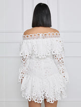 Back view of a model wearing a white off-the-shoulder eyelet lace mini dress with bell sleeves and ruffled trim.