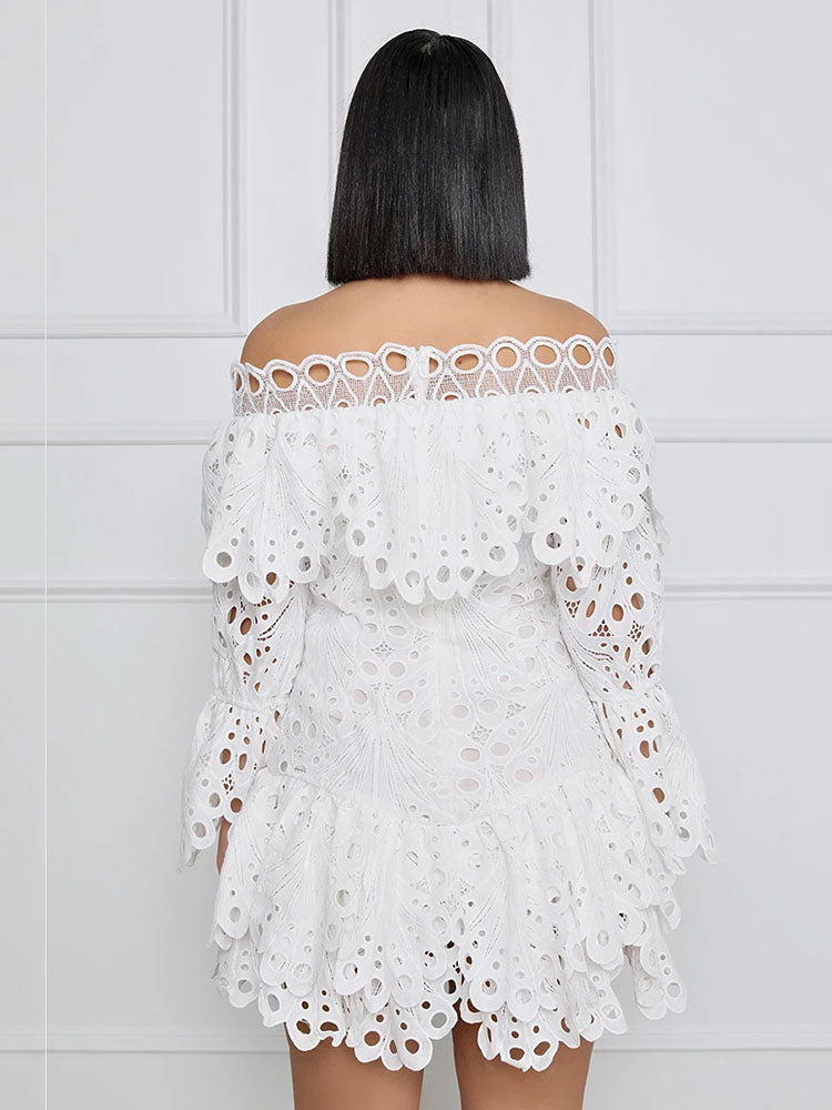 Back view of a model wearing a white off-the-shoulder eyelet lace mini dress with bell sleeves and ruffled trim.