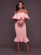 Woman wearing a pink off-the-shoulder ruffle dress and gold heels, front view