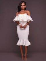 Woman wearing a white off-the-shoulder ruffle dress and gold heels, front view