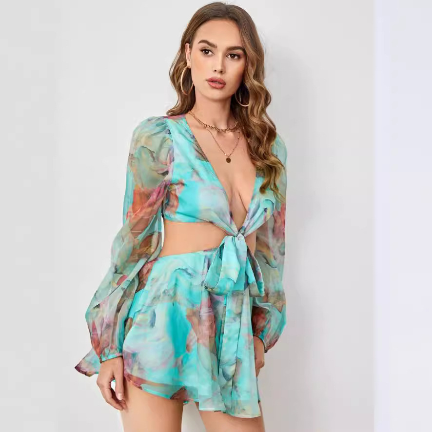 Woman wearing a turquoise and pink floral print two-piece set with a deep V-neck, front tie, and cut-out detail.