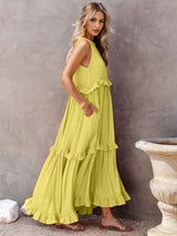 woman wearing a yellow tiered ruffle maxi dress with a halter neckline and smocked detail, shown from the side