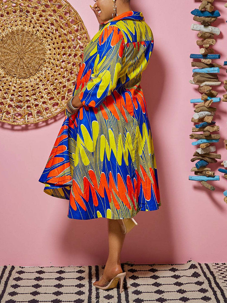 Woman showing the back of a colorful printed high-low dress with 3/4 sleeves and pockets.
