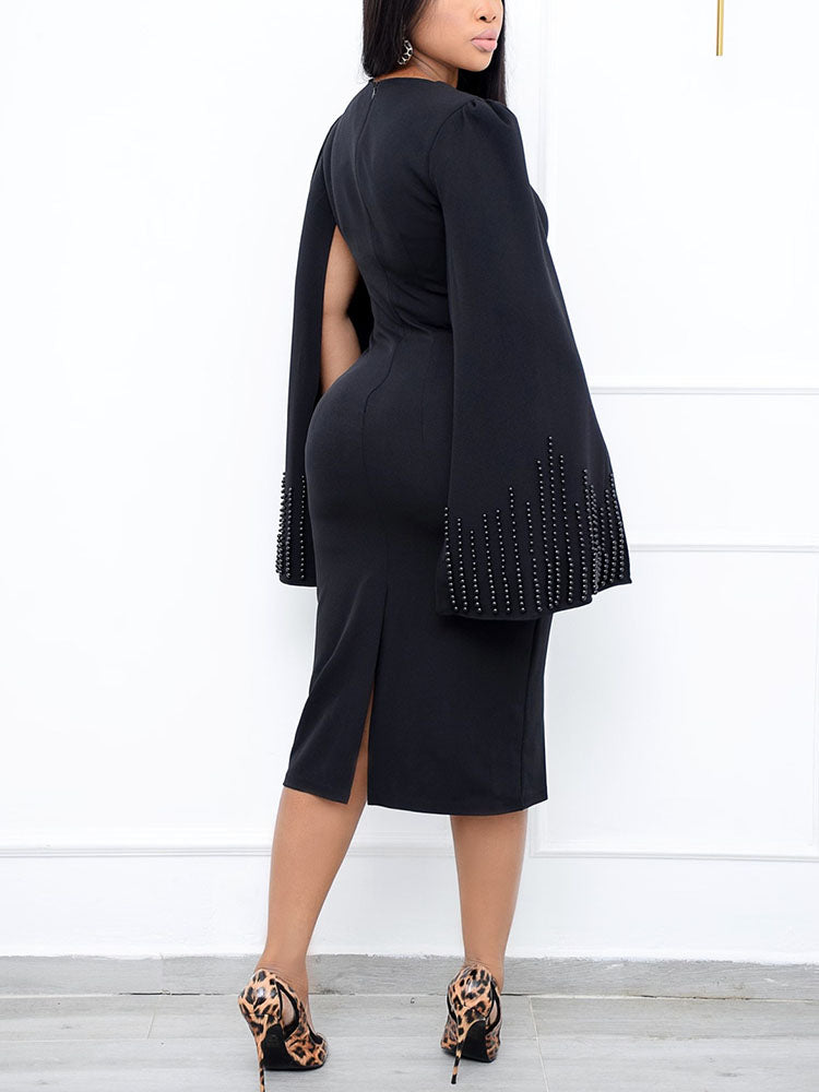 Back view of a woman in a black knee-length dress with cape sleeves and a square neckline.