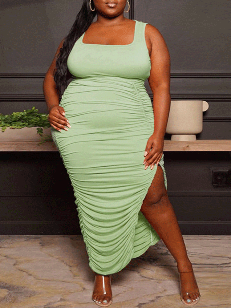 woman wearing a light green ruched midi dress with a square neckline and high slit