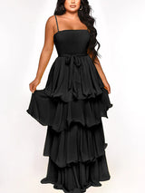 Woman wearing a black tiered maxi dress with spaghetti straps and a tie waist.