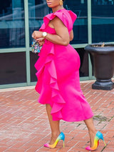 Rear side view of a woman in a fuchsia pink ruffled dress, emphasizing the back and the flow of the ruffles.