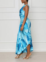 Woman wearing a blue tie-dye one-shoulder pleated maxi dress from the side, showing cut-out detail.