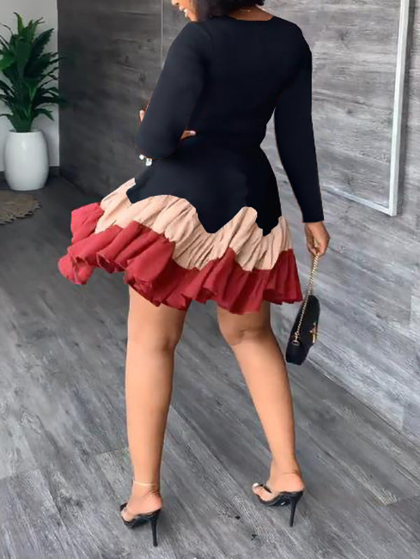 Back view of a woman in a black long-sleeved dress with a tiered, ruffled hem.
