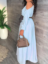 Side view of a woman in a long, off-the-shoulder light blue dress with a dark tie-waist belt, holding a handbag.