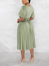 Back view of a woman in a light green midi dress with a cinched waist