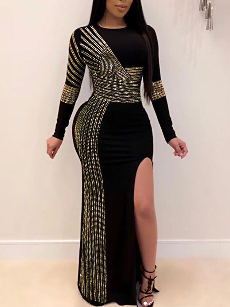 Woman wearing a black long-sleeved maxi dress with gold embellishments and a high slit.