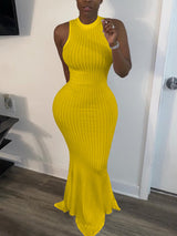 Woman wearing a yellow sleeveless ribbed knit maxi dress with a mermaid hem and mock neckline.