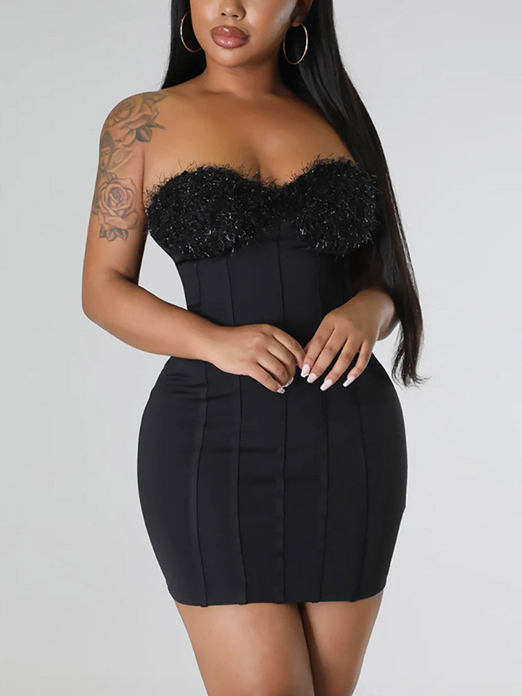 Front close-up of a woman wearing a black strapless dress with a fuzzy bust detail.