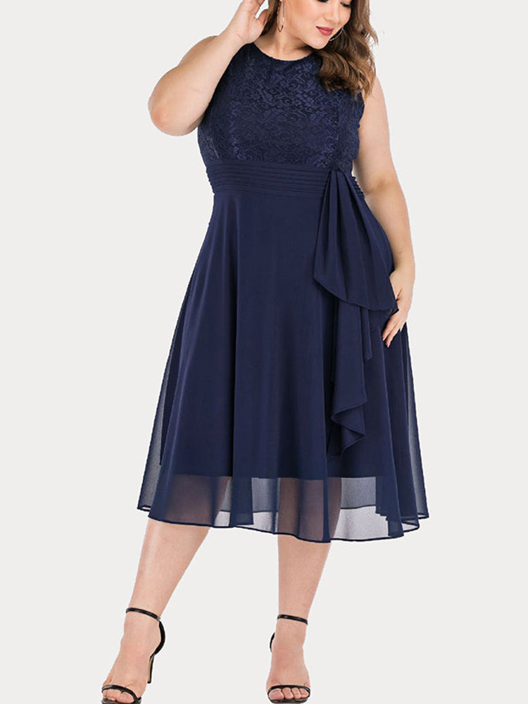 Full view of a woman in a navy blue sleeveless lace and chiffon dress with a knee-length hem