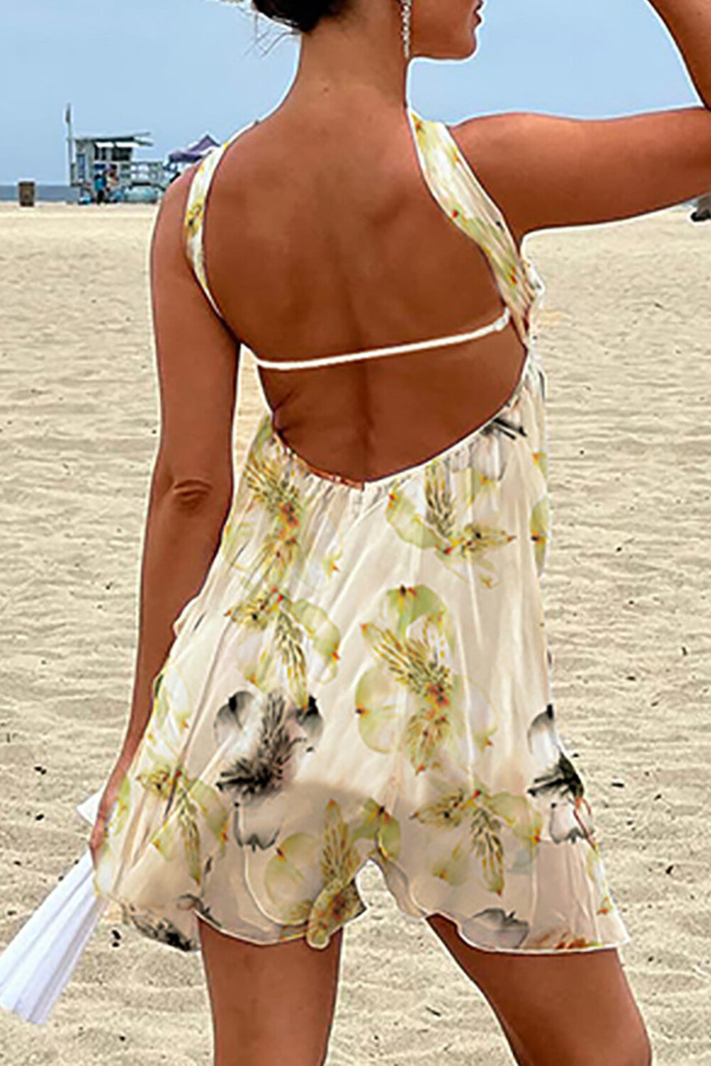back view of a woman wearing a floral print halter dress with an open back on the beach