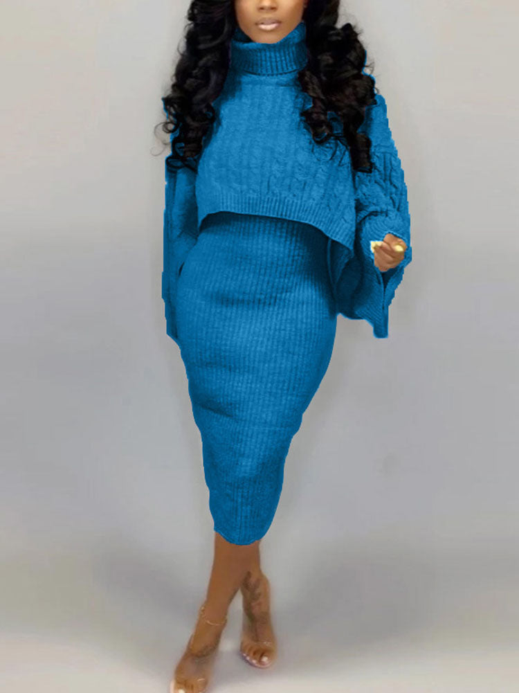 Full body shot of a woman in a blue cable knit sweater and ribbed knit skirt.