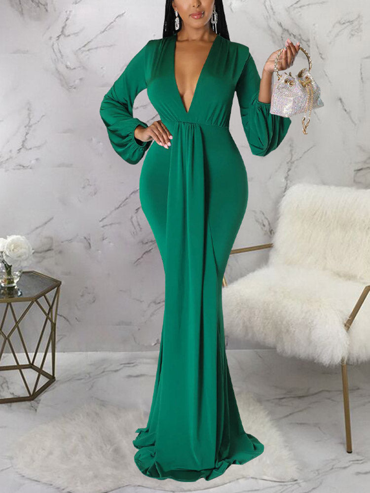 Woman holding a small embellished handbag while wearing an emerald green formal dress.