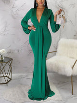 Woman holding a small embellished handbag while wearing an emerald green formal dress.