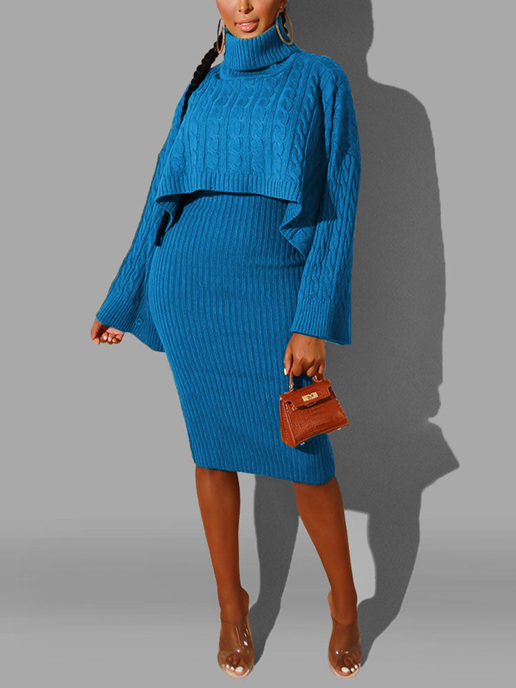 Woman with a braided hairstyle wearing a blue cable knit sweater and ribbed knit skirt, holding a small brown handbag.