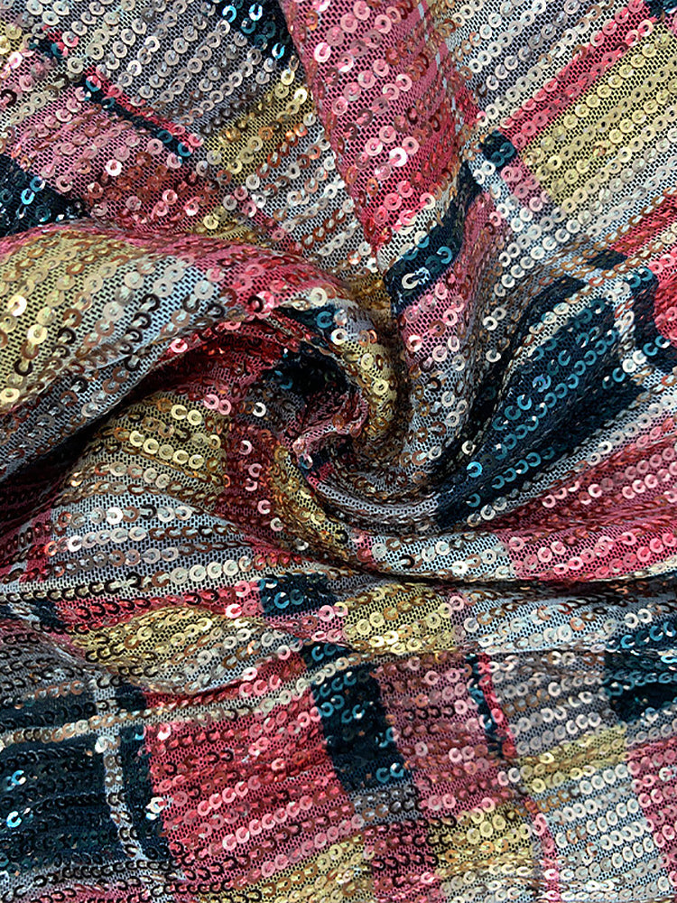Close-up of the sequined fabric with a plaid pattern in shades of red, gold, black, and cream.