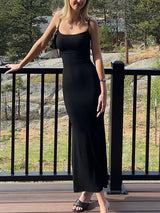 Woman in a black spaghetti strap maxi dress standing on a deck