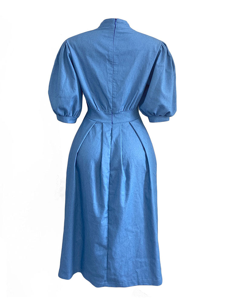 Back view of a blue denim midi dress with puffed sleeves and a pleated skirt, displayed on a white background.