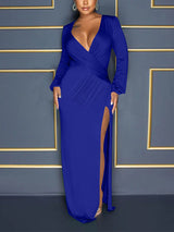Front view of a woman in a royal blue long-sleeve maxi dress with a deep V-neckline and a high slit.