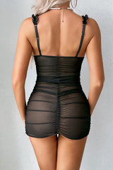 Back view of a woman in a black sheer mesh babydoll dress showing ruched detailing.