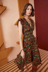 Woman wearing a green and orange patterned metallic jacquard midi dress with ruffled sleeves and a V-neckline.