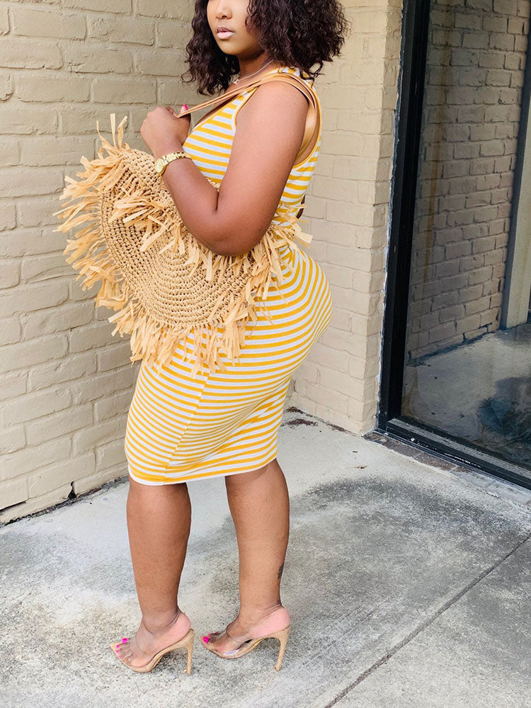 Side view of a woman wearing a yellow and white striped sleeveless dress with a scoop neckline.
